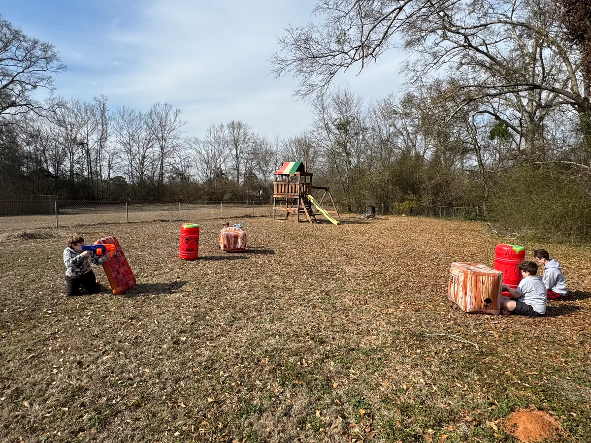 Kids playing a Nerf battle from behind inflatable cover