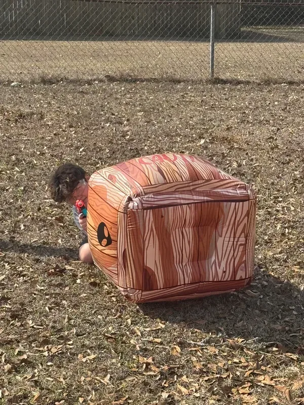 Child hiding behind a brick-wall inflatable barrier