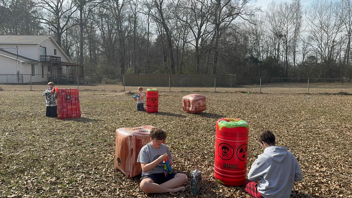 Players crouching behind barrel and crate barriers