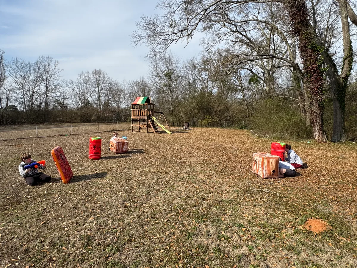 Wide view of a backyard Nerf battlefield with inflatable barriers